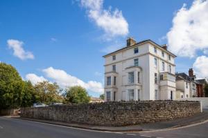 a large white house behind a stone wall at Sea View 2 Bed Apartment No 6 in Ryde
