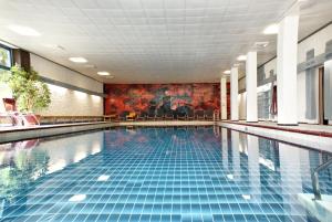 a large swimming pool with blue tiles in a building at Sporthotel Walliser in Hirschegg