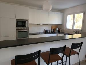 uma cozinha com armários brancos e um balcão com cadeiras em Maison bord de mer - la Tranche sur mer em La Tranche-sur-Mer