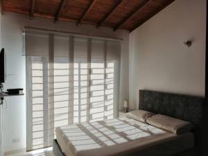 Bett in einem Zimmer mit einem großen Fenster in der Unterkunft Casa Rionegro Aeropuerto in Rionegro