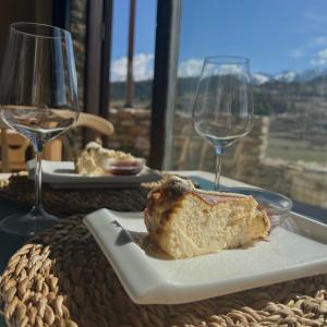 um prato com um pedaço de pão numa mesa com dois copos de vinho em LA HOSTERIA DE TOLORIU, el alt Urgell em Toloríu