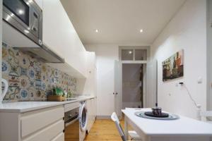 a white kitchen with a sink and a dishwasher at Pink Street Apartment in Lisbon