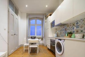 a kitchen with a table and a washing machine at Pink Street Apartment in Lisbon