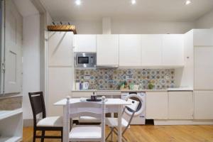 a kitchen with white cabinets and a table and chairs at Pink Street Apartment in Lisbon