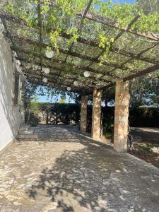 an outdoor patio with a stone structure with trees at Villetta Greco - Torre Lapillo in Porto Cesareo