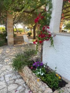 a garden with flowers and a stone wall at Villetta Greco - Torre Lapillo in Porto Cesareo