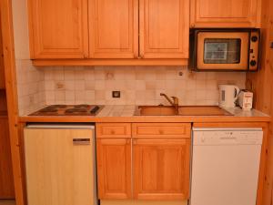 Kuchnia z drewnianymi szafkami, zlewem i kuchenką mikrofalową w obiekcie Studio lumineux au centre de Flaine avec balcon et kitchenette - FR-1-425-152 w mieście Flaine