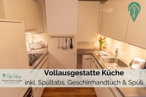 een keuken met witte kasten en een spoelbak bij Haus Hamburg OG in Greetsiel