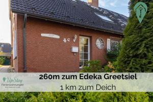 een bakstenen huis met een bord ervoor bij Haus Hamburg OG in Greetsiel