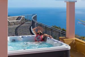 a woman sitting in a hot tub on a balcony at With jacuzzi sea view - Casa da Quinta Grande in Câmara de Lobos