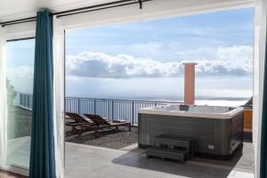 a bath tub on a balcony with a view of the ocean at With jacuzzi sea view - Casa da Quinta Grande in Câmara de Lobos