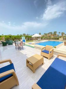 a patio with chairs and a swimming pool at فيلا للإيجار برايفت بول مارينا 5 الساحل الشمالي فيلا 5 غرف نوم مكيف بالكمال فرش فندقي in El Alamein