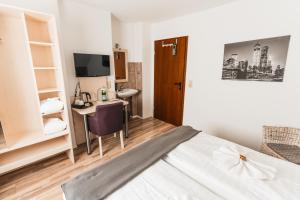 een slaapkamer met een bed, een bureau en een televisie bij Hotel Apartments Restaurant CALA LUNA in Marburg an der Lahn