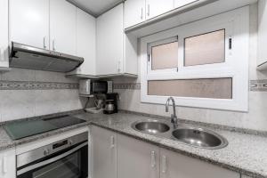 una cocina con armarios blancos y fregadero en Apartamento Pau Picasso con terraza Tossa de Mar, en Tossa de Mar