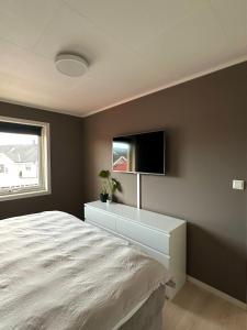 um quarto com uma cama e uma televisão na parede em Steiroveien em Sortland