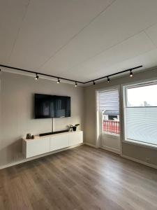 een lege woonkamer met een flatscreen-tv aan de muur bij Steiroveien in Sortland