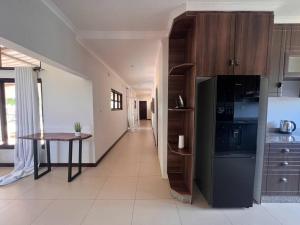 een keuken met een tafel en een zwarte koelkast bij Bantuz House in Livingstone