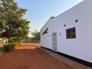 a white building with a door and a dirt road at Bantuz House in Livingstone