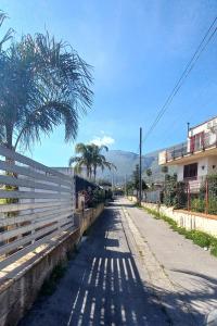 eine leere Straße mit einem Zaun und einer Palme in der Unterkunft Villa Annamaria in Carini
