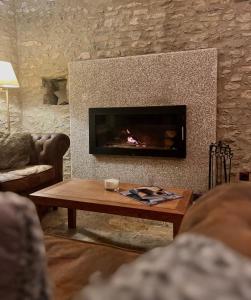 a living room with a fireplace and a coffee table at LA HOSTERIA DE TOLORIU, el alt Urgell in Toloríu