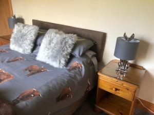 Una cama con almohadas peludas y una mesa con lámpara. en The Woolly Rock, en North Ballachulish