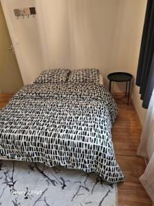 uma cama com um edredão preto e branco e uma mesa em Magnifique chambre em Beauvais