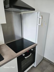 uma cozinha com um frigorífico e um fogão forno superior em Magnifique chambre em Beauvais