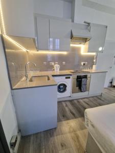 a kitchen with white cabinets and a sink and a dishwasher at Baker Street Suites in London