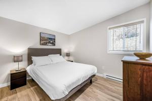 a white bedroom with a large bed and a window at Family-friendly Cottage with amazing views in West Kelowna