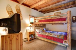 a bedroom with two bunk beds and a flat screen tv at Cozy Easton Cabin with Wenatchee Natl Forest Views! in Cabin Creek