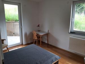 Schlafzimmer mit einem Schreibtisch, einem Bett und einem Fenster in der Unterkunft Ferienwohnung mit Neckarblick in Eberbach