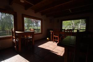 a dining room with a table and chairs and windows at Hostel Luz Clara in El Hoyo