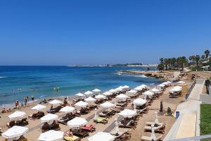 een strand met parasols en de oceaan bij Hotel complex house near the beach in Paphos City