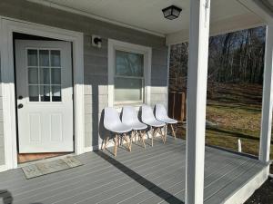 a group of white chairs sitting on a porch at Modern Luxury Home With Fireplace & Game-Room in Brockton