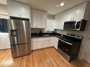 a kitchen with white cabinets and a stainless steel refrigerator at Modern Luxury Home With Fireplace & Game-Room in Brockton