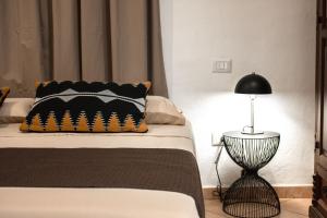 a bed with a black pillow and a lamp at Castello's Rooms in Cagliari