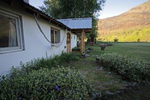 una casa blanca con una ventana junto a un campo en Hostel Luz Clara en El Hoyo