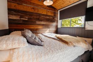 ein Schlafzimmer mit einem Bett mit einer Holzwand in der Unterkunft Cefn Crib Cabins in Machynlleth