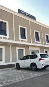 فندق دره الراشد للشقق المخدومه في الرياض: سيارة بيضاء متوقفة أمام مبنى