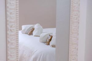 - un lit blanc avec des oreillers blancs et un miroir dans l'établissement El Deseo del Carmen, à El Burgo de Osma