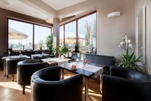 a restaurant with black chairs and tables and windows at Holiday House Europa in Rewal