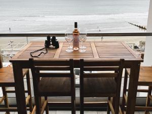 a wooden table with a bottle of wine and two glasses at 25 Breakwaters - Pet friendly in Sandown