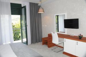 uma sala de estar com uma secretária, uma televisão e uma janela em Hotel Porto In em Kotor