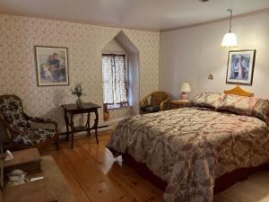 um quarto com uma cama, uma cadeira e uma janela em Manoir Guay Lafontaine em Rimouski