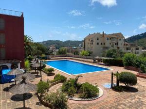 a swimming pool with umbrellas in a courtyard at Apartamento Pau Picasso con terraza Tossa de Mar in Tossa de Mar