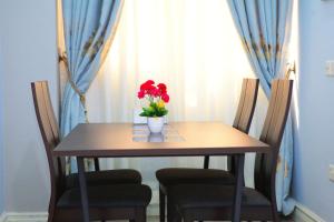 einen Tisch mit einer Vase mit roten Blumen darauf in der Unterkunft Vovole Luxury Homes in Kwedonu