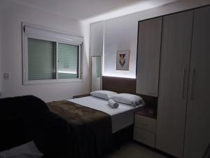 a bedroom with a bed and a dresser and a window at Loft Central in Passo Fundo