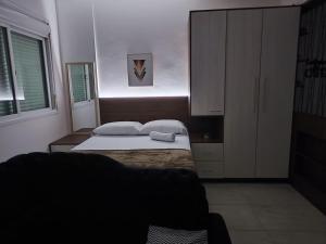 a small bedroom with a bed and a cabinet at Loft Central in Passo Fundo