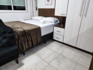 a small bedroom with a bed and a chair at Loft Central in Passo Fundo