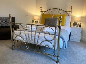 1 dormitorio con cama de metal y almohadas amarillas en 4 The Bayhouse, en Shanklin